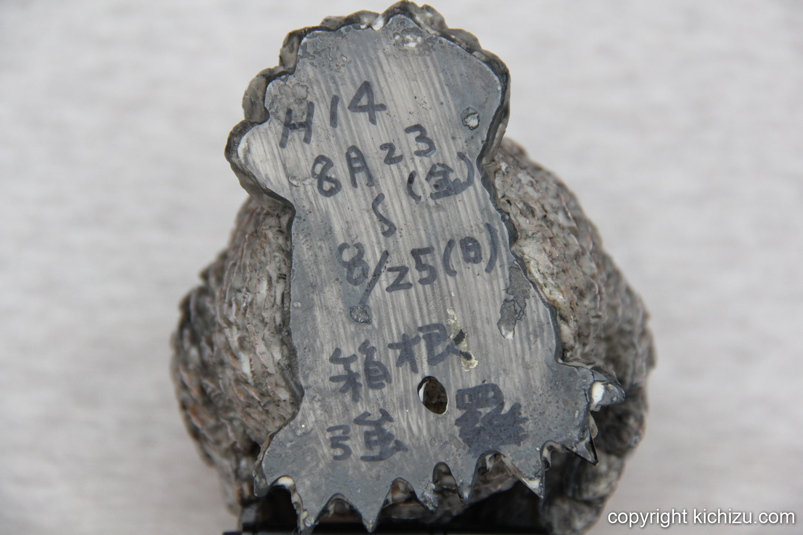 The underside of the feet of the wooden owl figurine.